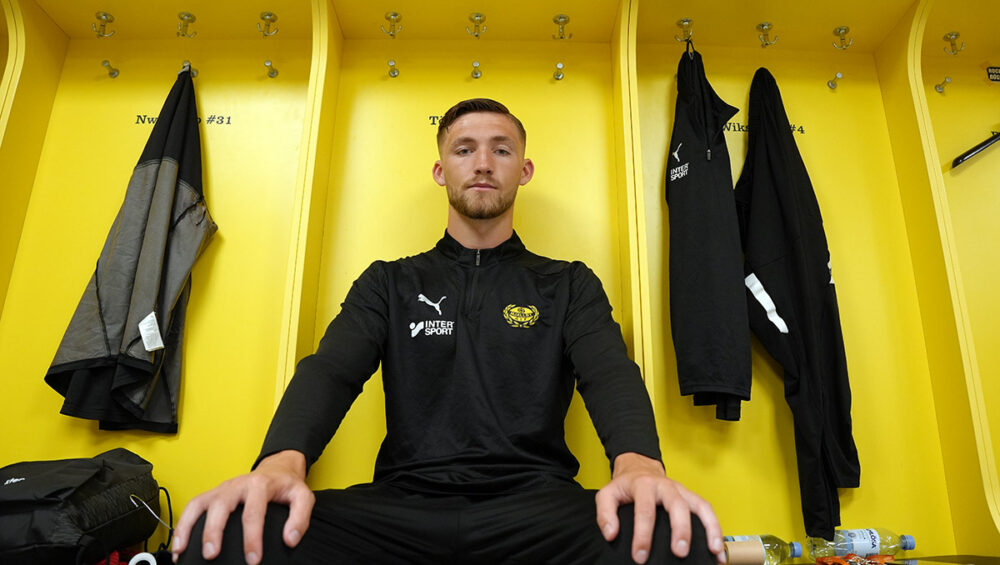 Bild på Noel Törnqvist sittandes i Mjällby AIF:s omklädningsrum.